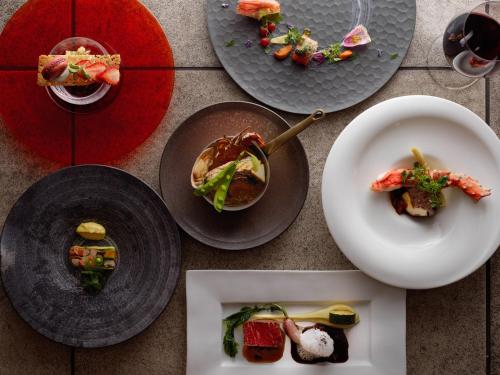 una mesa con platos de comida y copas de vino en Hakodate Onuma Tsuruga Resort EPUY, en Nanae