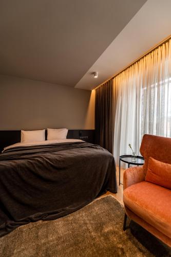 a bedroom with a bed and a chair and a window at Maestro Design Hotel in Liepāja