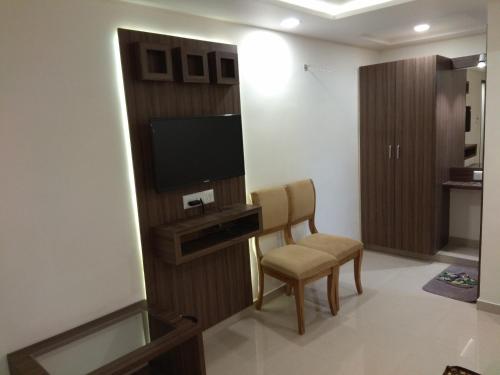 uma sala de estar com uma televisão e uma cadeira num quarto em Hotel Shobhna Palace em Ahmedabad