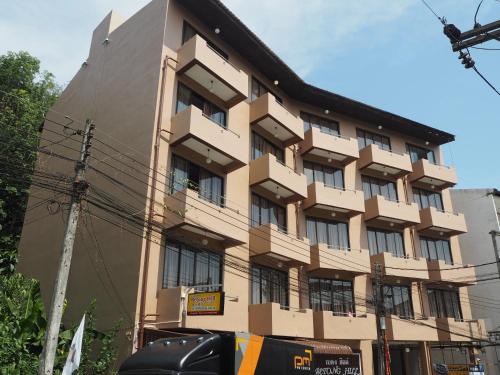 a brown building with windows and a street at Betong Hill Hotel โรงแรมเบตง ฮิลล์ in Betong