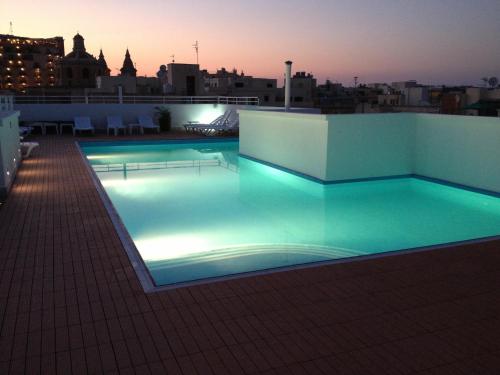 a swimming pool on the roof of a building at night at Day's Inn Hotel and Residence in Sliema
