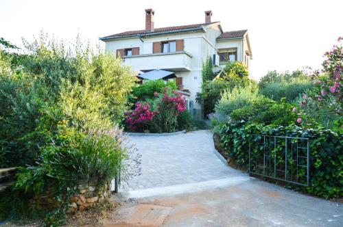 a house with a gate in a garden with flowers at Apartment Zoja in Pinezici