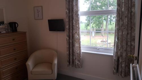 a room with a chair and a window at Chequers Inn in Fladbury