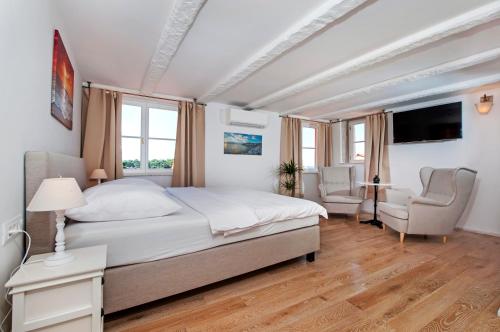 a bedroom with a large bed and two chairs at Casa Colloredo Free Parking in Rovinj