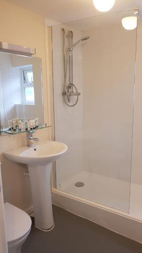 a white bathroom with a sink and a shower at Chequers Inn in Fladbury