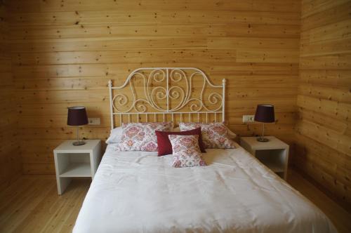 ein Schlafzimmer mit einem weißen Bett mit zwei Tischen und zwei Lampen in der Unterkunft Satia Berri in Llanteno