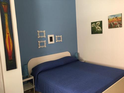 アグリジェントにあるAntonio's Houseのベッドルーム1室(青いシーツと壁に絵画が飾られたベッド1台付)