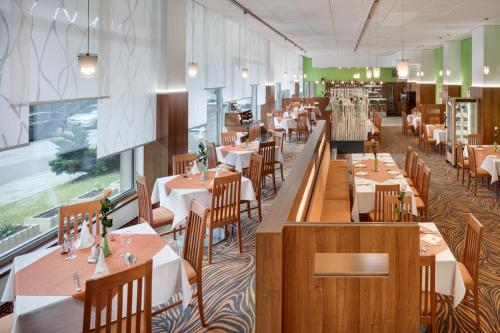 ブルノにあるアヴァンティ ホテルの木製テーブルと椅子、テーブルサーチャー付きのレストラン