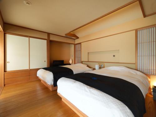 two beds in a room with wooden floors at Akan Tsuruga Besso Hinanoza in Akankohan