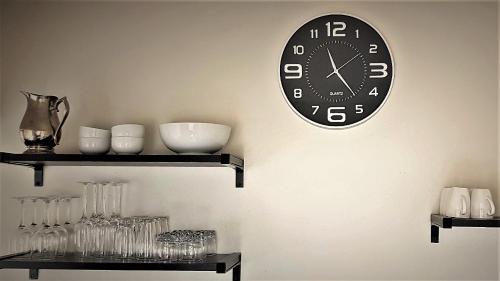 a clock hanging on a wall with glasses on shelves at Graceland Eco Retreat in Magoebaskloof