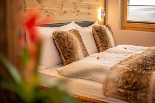 a bed with white pillows and brown pillows at Palace Luxury Wellness Apartment and Boutique Hotel Ski-in-out in Saas-Fee