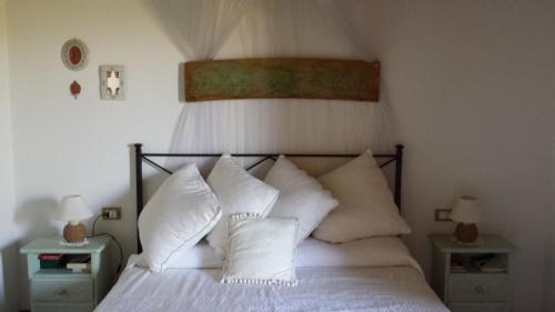 a bedroom with a white bed with white pillows at Residenze Coda Cavallo in San Teodoro