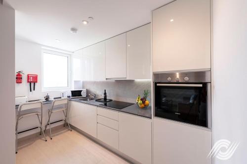 a kitchen with white cabinets and white appliances at Westone Luxury Self Catered Apartments in Gibraltar