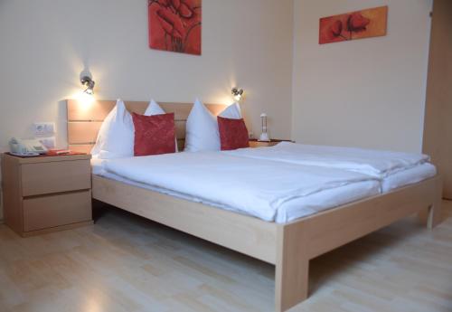 een slaapkamer met een bed met witte lakens en rode kussens bij Hotel Bergkristall in Schwarzenberg am Bohmerwald
