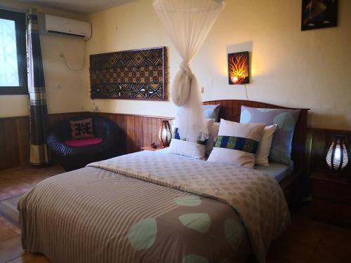 1 dormitorio con 1 cama grande y 1 silla en Joli jardin en ville en Yaundé