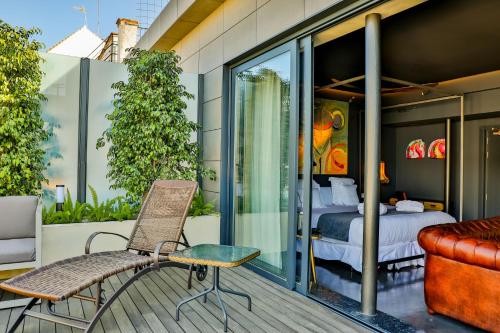 a room with a bed and a chair on a balcony at Hotel Lobby in Seville