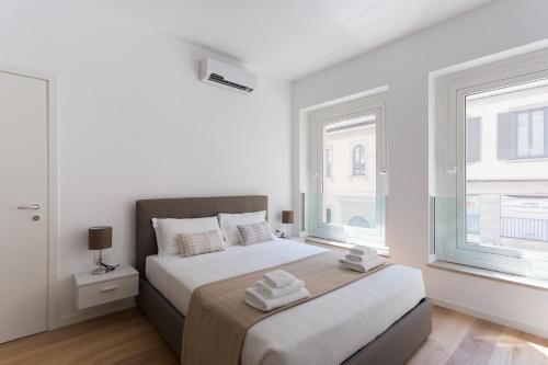 um quarto branco com uma cama e 2 janelas em Meravigli 16 - Apt B - Duomo Elegant Apartment! Self Check-In em Milão