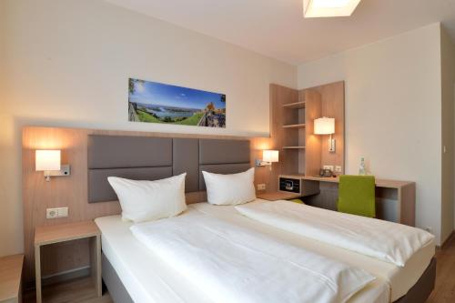 a hotel room with a large white bed and a desk at City-Hotel Kurfürst Balduin in Koblenz