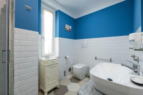 La salle de bains bleue et blanche est pourvue d'une baignoire et de toilettes. dans l'établissement Guest House - Il Cedro Reale, à Venaria Reale