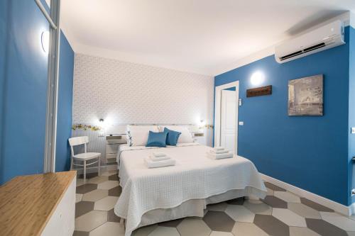 Guest House - Il Cedro Reale في فيناريا ريالي: غرفة نوم زرقاء مع سرير وطاولة