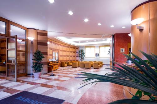a lobby with a waiting area with chairs and plants at Hotel Persico's in San Giovanni in Persiceto