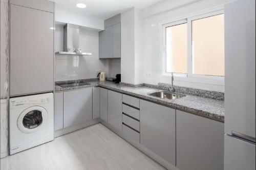 een witte keuken met een wastafel en een wasmachine bij La Merced RooMalaga by Bossh! Apartments in Málaga