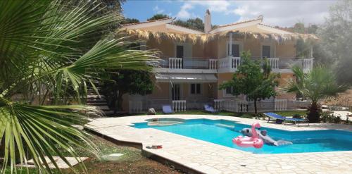a villa with a swimming pool in front of a house at Doroufi Inn in Koilás