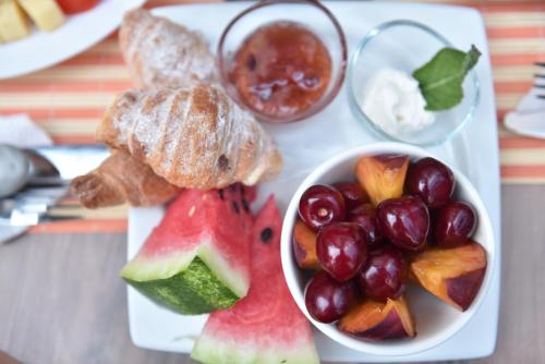 a plate with a bowl of fruit and a bowl of bread at Prior Hotel in Prizren