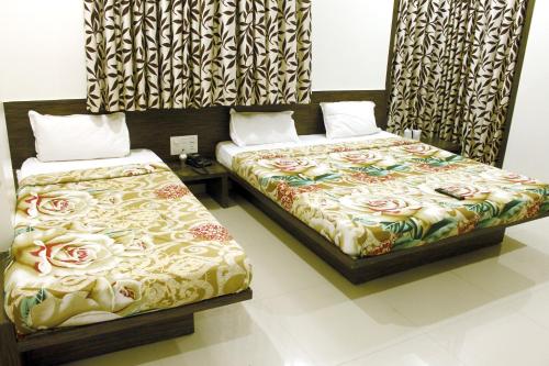 duas camas sentadas uma ao lado da outra num quarto em Hotel Shradha Saburi Palace em Shirdi