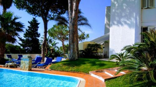 a swimming pool with blue lounge chairs and a house at Vento Verde Apartments in Sperlonga