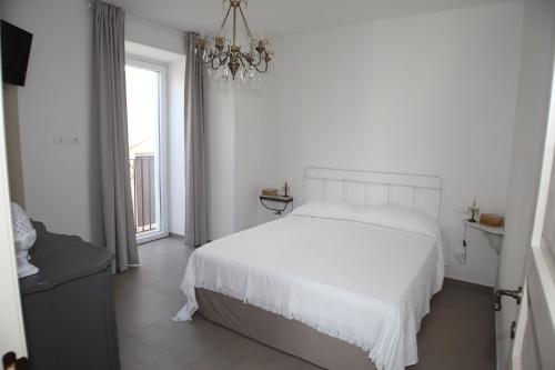a white bedroom with a white bed and a chandelier at Don Alfredo in Taranto
