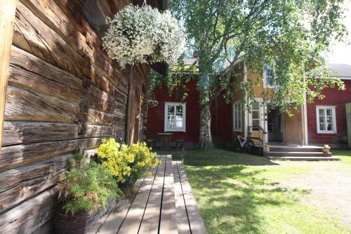 a house with a wooden wall and flowers in front of it at LAURI Historical Log House Manor in Rovaniemi