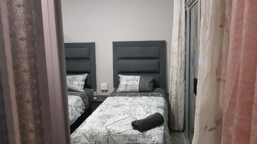 1 Schlafzimmer mit 2 Betten mit schwarzen Kopfteilen in der Unterkunft 10 South Apartments in Durban
