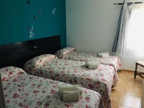 three beds in a room with green walls at Hostal Catedritos Ibéricos A-5 Km 154 A 5 KM DE OROPESA A 1 KM DE HERRERUELA DE OROPESA in Herreruela de Oropesa