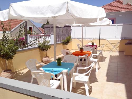 a patio with tables and chairs and an umbrella at Villa Romantza in Fiskardho