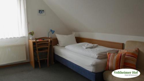 a small bedroom with a bed and a table at Landgasthaus Veltheimer Hof in Porta Westfalica