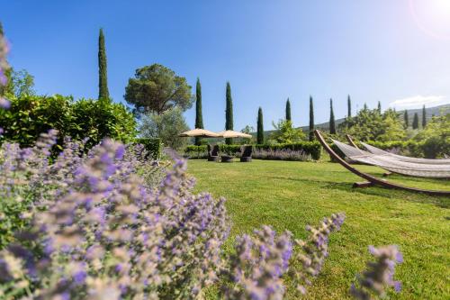 a garden with purple flowers and a hammock and trees at Borgo dé Brandi in Monteriggioni