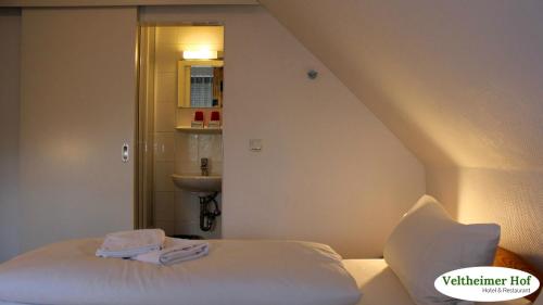 a small bedroom with a bed and a sink at Landgasthaus Veltheimer Hof in Porta Westfalica
