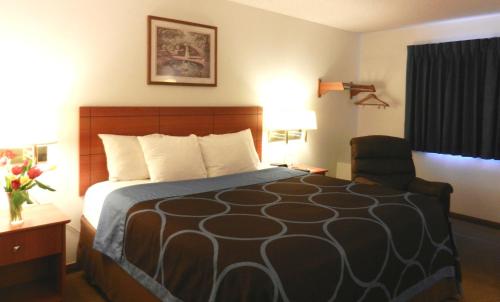 a hotel room with a bed and a chair at Super 8 by Wyndham Manhattan KS in Manhattan