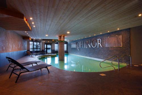 a swimming pool in a hotel with a sign on the wall at Résidence Koh-I Nor by Les Etincelles in Val Thorens