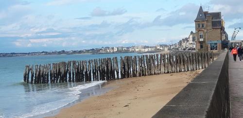 een strand met een hek en de oceaan en een gebouw bij La Marinière Hôtel Restaurant Crêperie in Saint-Malo