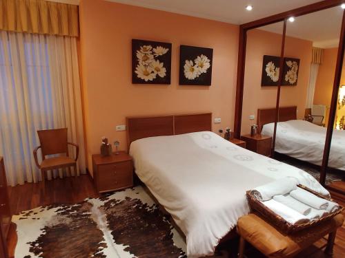 1 dormitorio con 1 cama grande y espejo en Hogar, a modo de hotel en Gijón