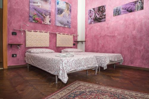 a room with two beds and a pink wall at A Casa Fachin Room & Breakfast in Bologna