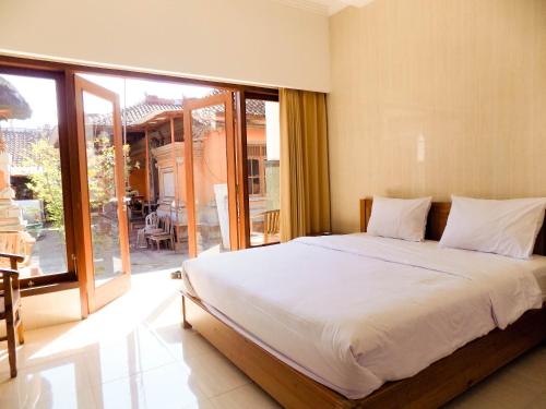 ein Schlafzimmer mit einem großen Bett und einem großen Fenster in der Unterkunft Guna Graha Kuta by Kamara in Kuta