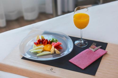 a plate of fruit and vegetables and a glass of orange juice at Hotel Puerta de Bilbao in Barakaldo