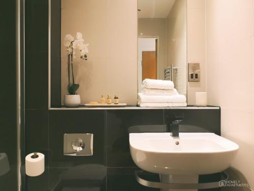 a bathroom with a white sink and a mirror at Homely Serviced Apartments - Blonk St in Sheffield