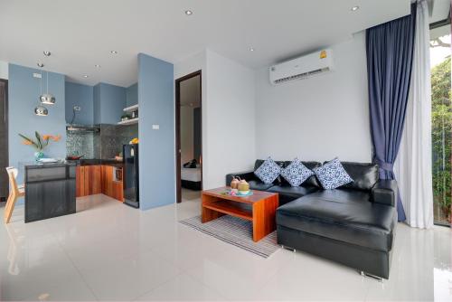 a living room with a black leather couch and a table at Coco Layma Villa, Samui in Lamai