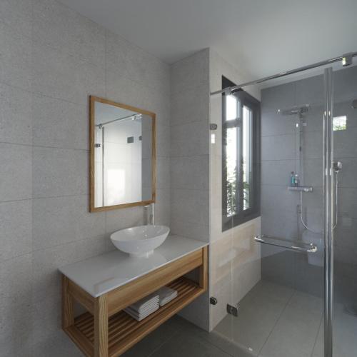a bathroom with a sink and a mirror and a shower at Lem's Apartment & Coffee in Danang