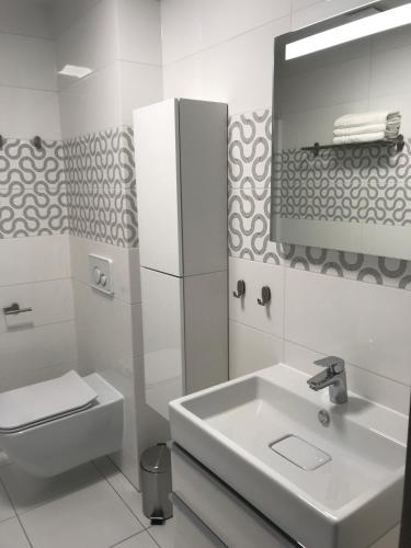 a white bathroom with a sink and a mirror at Apartamenty nad morzem & SPA BEST HOME 5 Mórz basen kryty in Sianozety