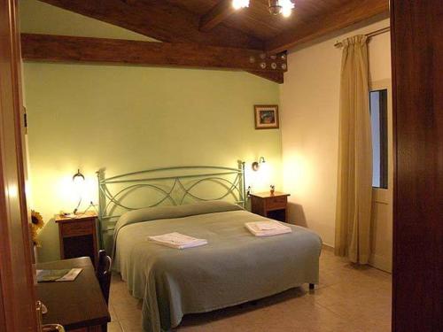 ein Schlafzimmer mit einem Bett, zwei Tischen und einem Fenster in der Unterkunft Agriturismo Le Frasche in Alberese